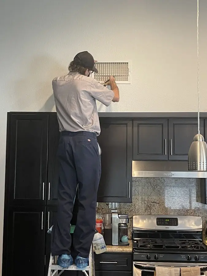 Technician inspecting an air vent during HVAC service in Millbrook